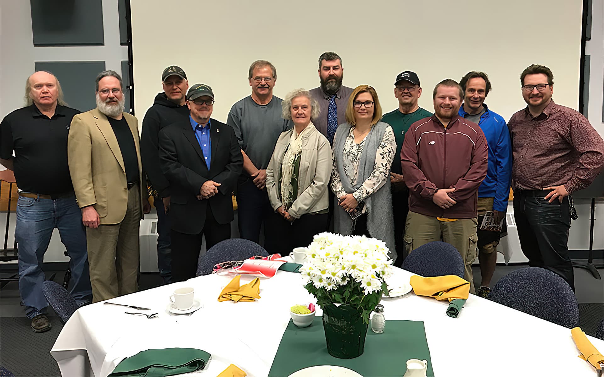 Employees being recognized pose standing together for a group photo in nadeau hall conference room