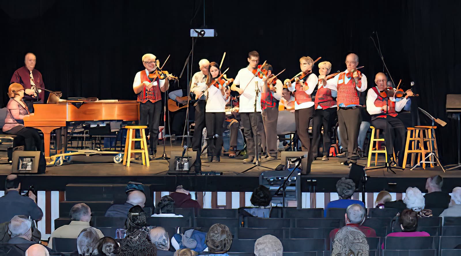 a group of fiddlers and a pianist perform on the stage at Fox Auditorium during a previous Fiddlers' Jamboree