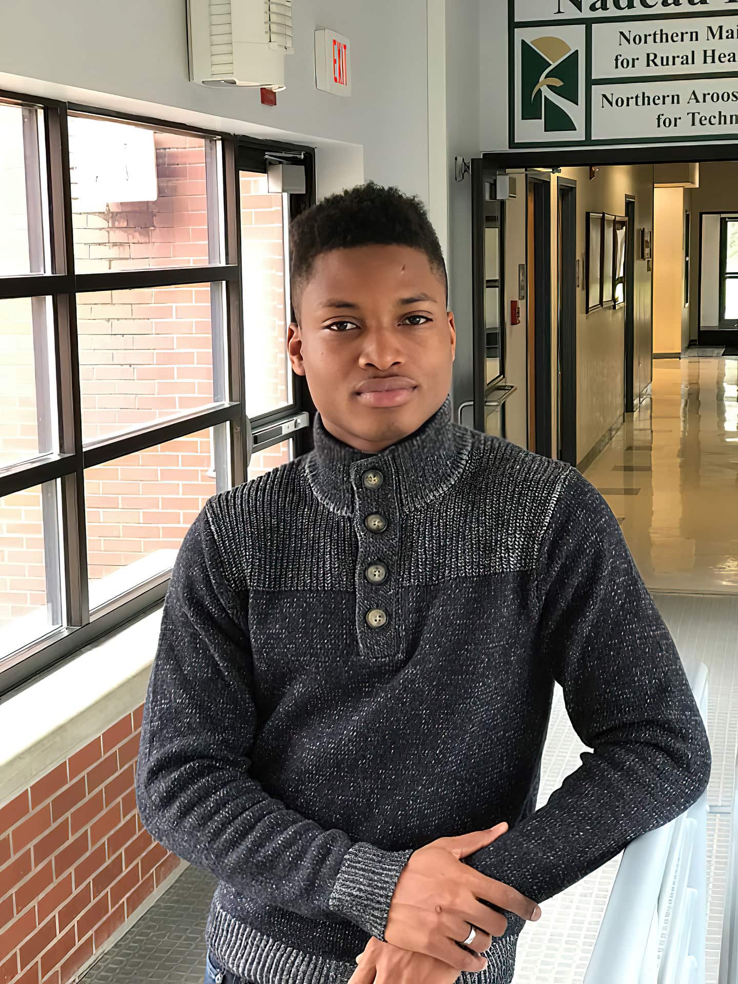 photo of UMFK student Glenroy Osbourne posing in the hallway leading to Nadeau Hall