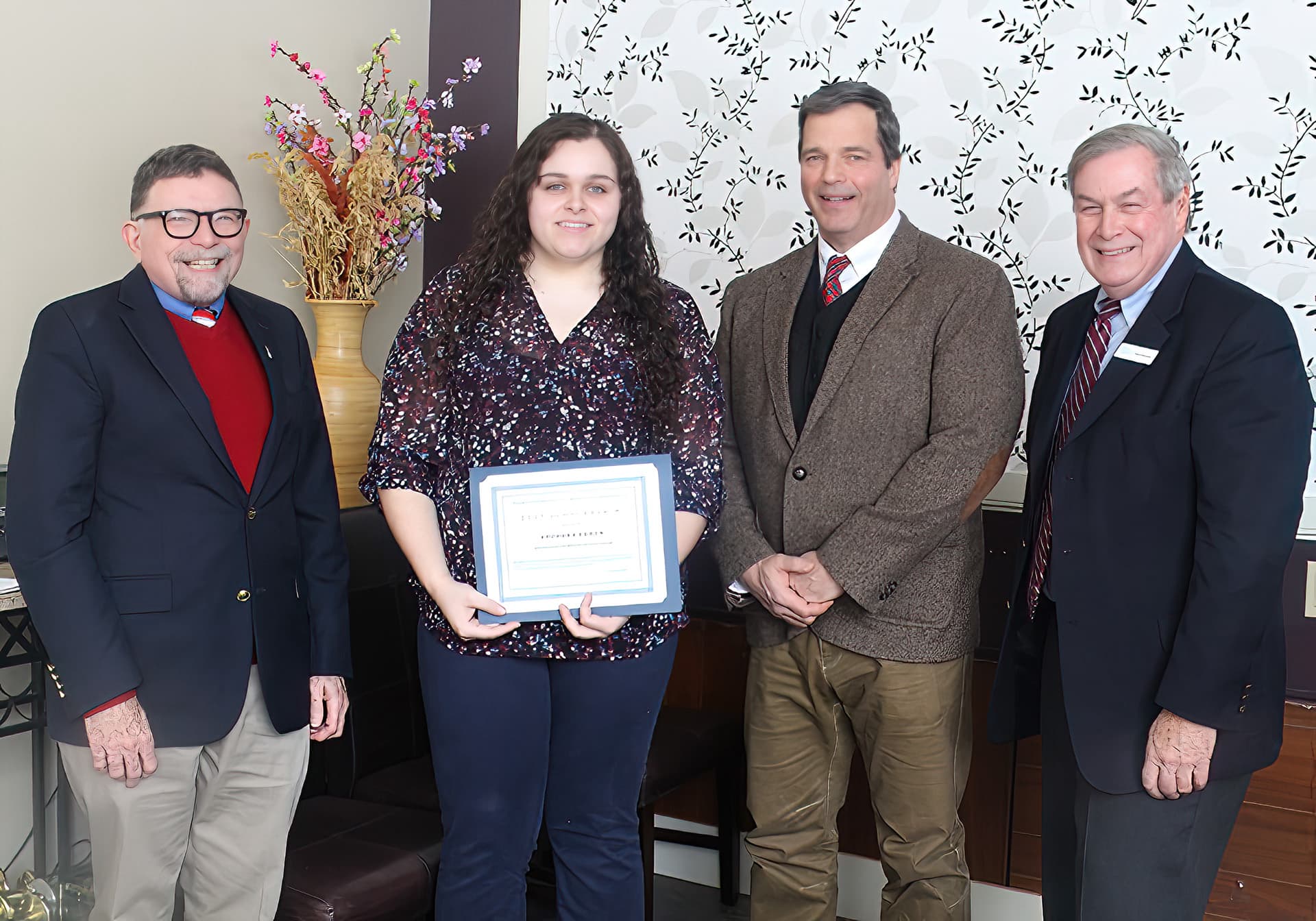 Scholarship recipient Steffany Caron holds a certificate presented to her by UMFK President Dr. John N. Short, Dr. Leo Trudel, and Chris W. Pinkham. Caron stands in the center, with Dr. Short to her right and Dr. Trudel and Mr. Pinkham to her left.