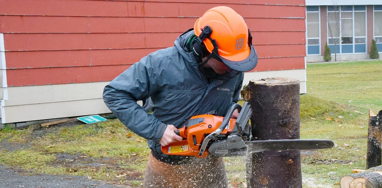 UMFK forestry student uses a chainsaw to cut a stump