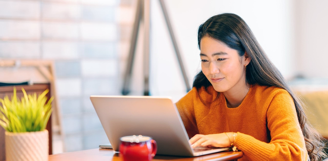 female student of asian descent types on her laptop