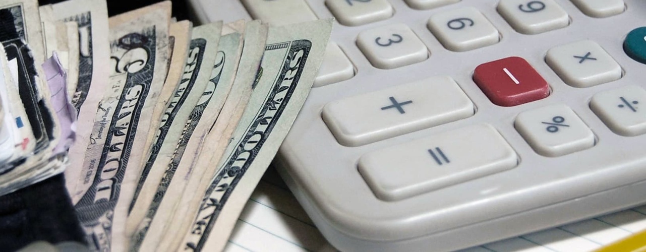 Wallet, calculator, and pad of paper lying on a desk