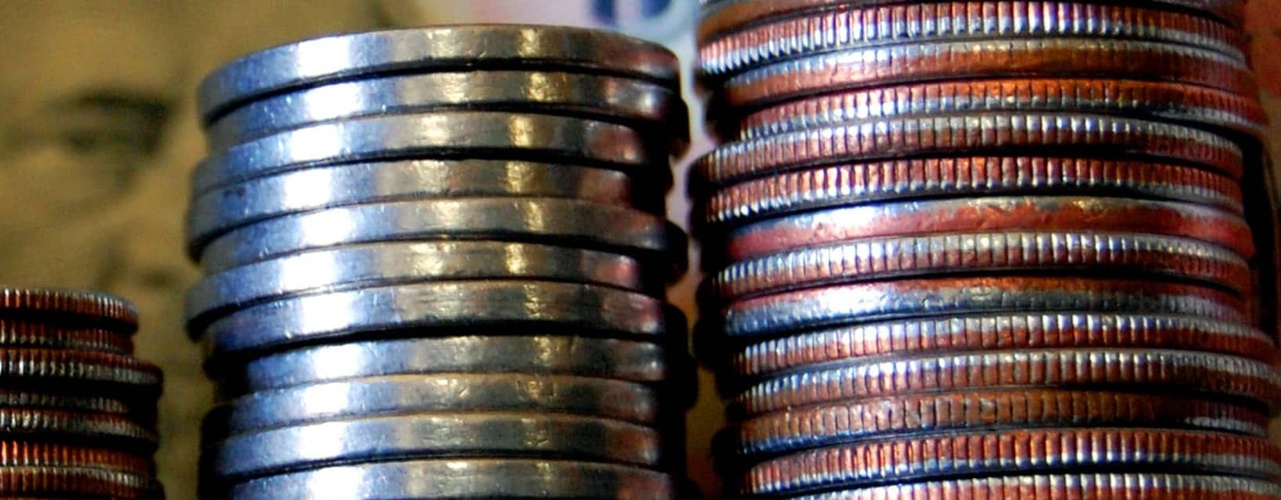 Coins stacked with a fifty dollar bill in the background