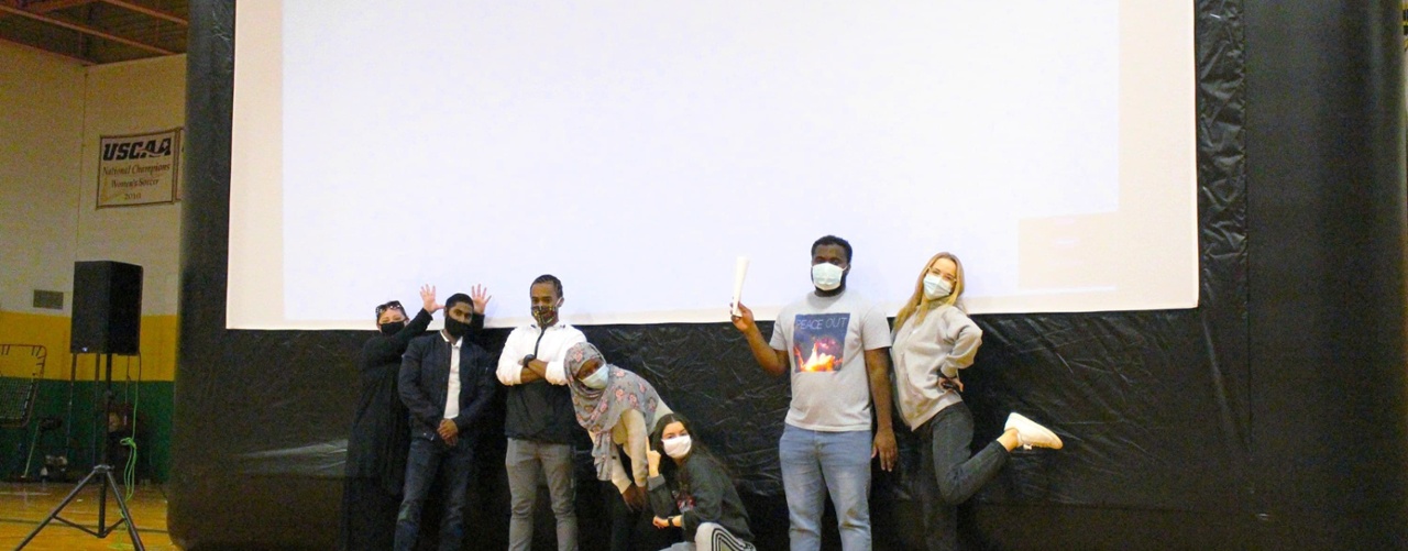 students pose in front of an inflatable movie screen at a movie night