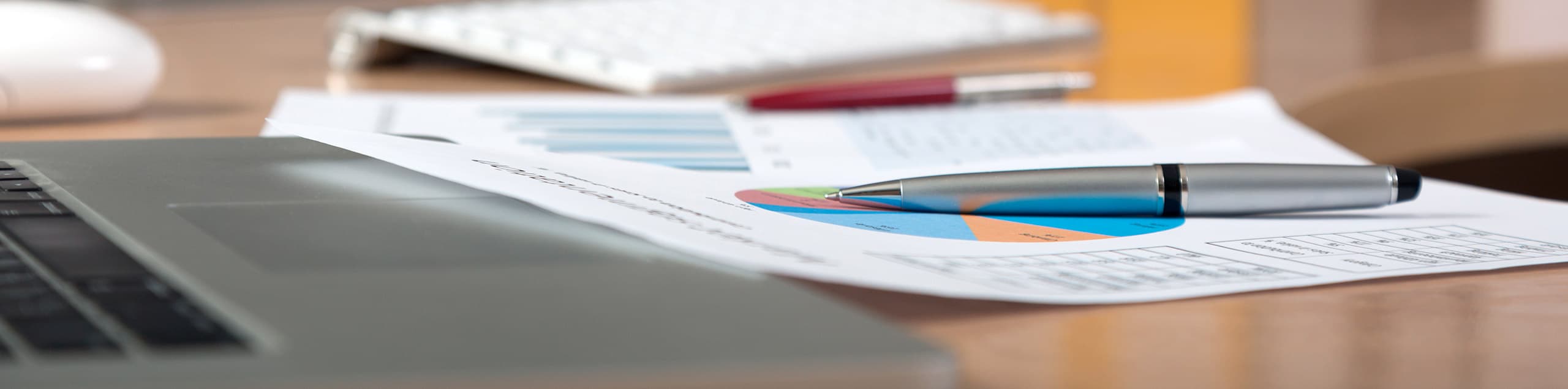 printout of graphs sitting on a desk near a laptop