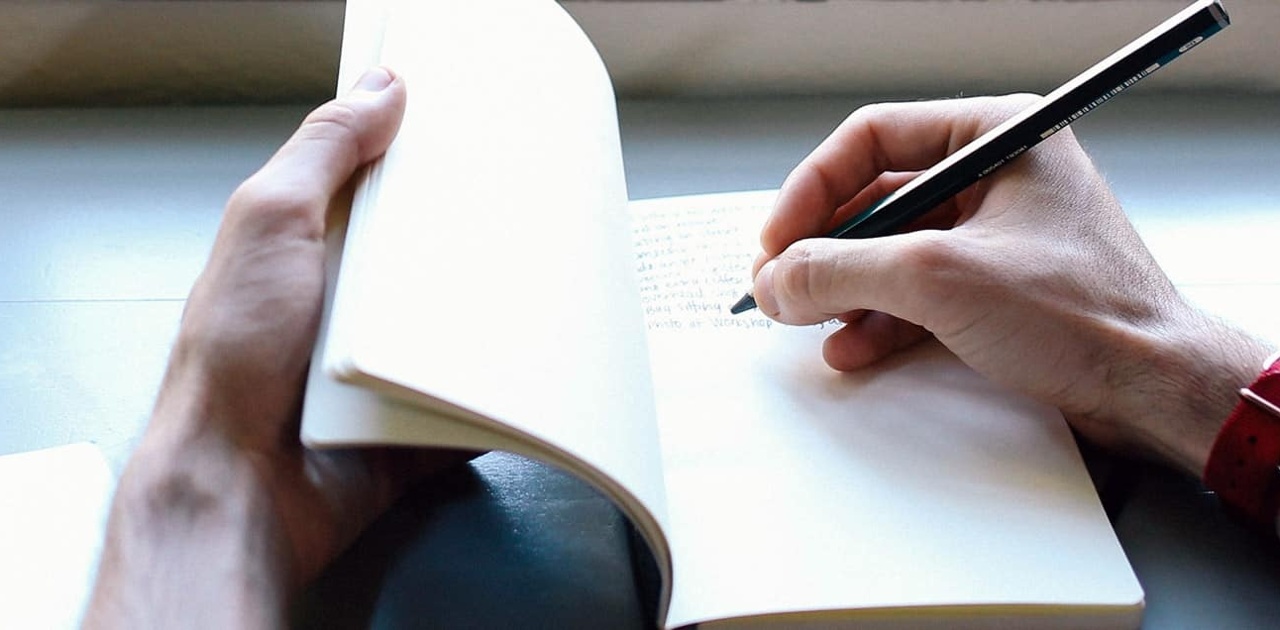 man writing in a journal