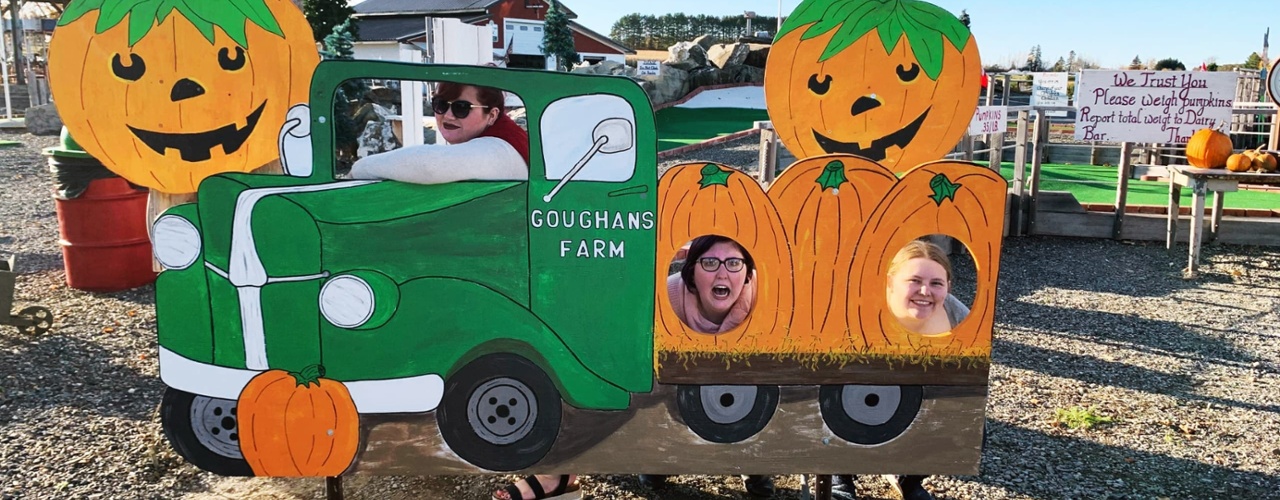 Students pose in a wooden photo prop at a local farm